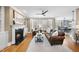 Inviting living room with fireplace, hardwood floors, ceiling fan, brown leather sofa, and large windows at 113 Woodland Ridge Ct, Cary, NC 27519