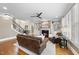 Open-concept living room boasts hardwood floors, a fireplace, a ceiling fan, and a leather sofa at 113 Woodland Ridge Ct, Cary, NC 27519