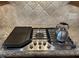 Close-up of a stainless steel Cafe stovetop with a griddle, burner, and granite countertops at 113 Woodland Ridge Ct, Cary, NC 27519