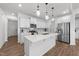 Bright kitchen with white cabinets, stainless appliances, quartz countertops and a large center island with pendant lighting at 125 Paperwhite Pl, Clayton, NC 27527