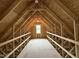 Unfinished attic with wooden beams and a small window at the end at 125 Tuskeegee Dr, Smithfield, NC 27577