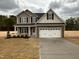 Inviting two-story home with stone accents, a two-car garage, and a well-manicured front yard at 125 Tuskeegee Dr, Smithfield, NC 27577