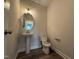 Cozy powder room with a pedestal sink, a round mirror, and neutral paint at 125 Tuskeegee Dr, Smithfield, NC 27577