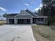 New construction home with three-car garage, black roof, light-green siding, and stone accents at 139 Red River Dr, Selma, NC 27576