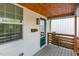 Inviting front porch featuring a light grey wood deck, dark-green door, white siding and a wood plank ceiling at 15 St Augustine, Raleigh, NC 27610