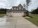 New two-story home showcasing a three-car garage, neutral siding, and professionally landscaped front yard on a cloudy day at 18 Bonnybrook Ct, Selma, NC 27576
