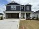 Two-story home boasts a dark blue facade, open garage and manicured front lawn at 18 W Emily Gardens Dr, Selma, NC 27576