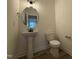 Clean half bathroom featuring a pedestal sink, a round mirror and wood floors at 21 Trescott St, Smithfield, NC 27577
