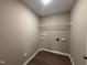 Clean, empty laundry room with connections for washer and dryer and shelving at 212 Tuscany Cir, Princeton, NC 27569