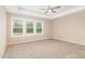 Spacious bedroom featuring plush carpeting, a tray ceiling, and three large windows for natural light at 212 Tuscany Cir, Princeton, NC 27569