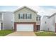 Two-story home featuring a white garage door, brick facade, green siding, and a well-manicured lawn at 2153 Monk Dr, Haw River, NC 27258