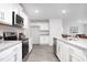 Galley-style kitchen boasts white cabinetry, stainless steel appliances, granite countertops, and wood-look flooring at 2153 Monk Dr, Haw River, NC 27258