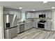 Well-lit kitchen featuring gray cabinets, stainless steel appliances, granite counters, and hardwood floors at 2316 Radiance Dr, Burlington, NC 27215
