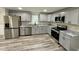 Well-lit kitchen featuring gray cabinets, stainless steel appliances, granite counters, and hardwood floors at 2316 Radiance Dr, Burlington, NC 27215