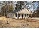 Quaint one-story home with a covered porch, black shutters, and neutral siding in a wooded setting at 303 E Pope Ave, Kenly, NC 27542