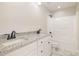 Modern bathroom with double vanity featuring granite countertops and white cabinets and shower with sleek black fixtures at 307 E Pope Ave, Kenly, NC 27542