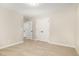 A bedroom with beige carpet, featuring double closets and two entry doors at 307 E Pope Ave, Kenly, NC 27542