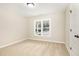 Cozy bedroom with neutral walls and carpet, featuring a bright window providing natural light and a view of the neighborhood at 307 E Pope Ave, Kenly, NC 27542