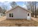 View of the rear exterior elevation featuring neutral siding, white door and window trim, and simple landscape at 307 E Pope Ave, Kenly, NC 27542