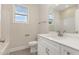 Bright bathroom featuring a white vanity, toilet, and gray tile flooring, complemented by a window offering natural light at 32 Bonnybrook Ct, Selma, NC 27576