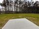 Large grassy backyard with a concrete patio, surrounded by a serene line of tall trees at 39 N Rowsham Pl, Smithfield, NC 27577