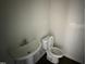 A simple bathroom with a pedestal sink, a toilet, and dark flooring at 43 Chloe Ct, Selma, NC 27577