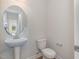 Bathroom with pedestal sink, toilet, round mirror, and neutral color scheme, creating a clean and simple design at 54 Barony Ln, Smithfield, NC 27577