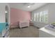 Cozy Bedroom with pink accent wall, crib, rocking chair and neutral carpet at 5928 Terrington Ln, Raleigh, NC 27606