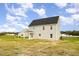 Side view of the home showcasing its neutral siding, covered porch, and spacious backyard at 65 Barony Ln, Smithfield, NC 27577