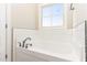 Bathroom featuring a drop-in tub with chrome faucet fixtures and a subway tile backsplash under the window at 68 Tee Dr, Selma, NC 27576