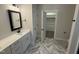 Modern bathroom with marble floors, double vanity, and a walk-in closet, blending style and functionality at 702 Tuscany Cir, Princeton, NC 27569