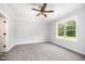 A carpeted bedroom with a ceiling fan and window overlooking a green lawn at 702 Tuscany Cir, Princeton, NC 27569