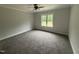 Bright bedroom with a ceiling fan, neutral carpet, and a large window offering serene outdoor views at 702 Tuscany Cir, Princeton, NC 27569