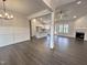 Open concept living area featuring hardwood floors, modern lighting, and fireplace with brick surround at 702 Tuscany Cir, Princeton, NC 27569