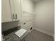 Laundry room with overhead shelf, cabinets, granite counters and tile flooring at 76 Royal Ave, Selma, NC 27576