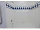Clean bathroom tub and shower with white tiles and an accent of blue and green patterned tiles at 7605 Mine Valley Rd, Raleigh, NC 27615