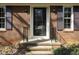 Close-up of the front door, featuring a brick facade, black shutters, and decorative iron railings at 7605 Mine Valley Rd, Raleigh, NC 27615