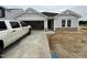 New construction, one-story home featuring light gray siding, stone accents, and an attached two car garage at 8 W Emily Gardens Dr, Selma, NC 27577