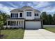 New two-story home with a white facade, black shutters, stone accents, and a spacious two-car garage at 83 W Emily Gardens Dr, Selma, NC 27576