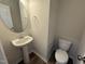 Newly constructed half bath with a pedestal sink, round mirror, modern fixtures, and a toilet at 83 W Emily Gardens Dr, Selma, NC 27576
