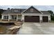 New construction home featuring a two-car garage, stone accents and neutral-colored siding at 87 Tee Dr, Selma, NC 27576