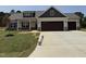 Charming home featuring tan siding, stone accents, a three-car garage, and manicured lawn at 87 Tee Dr, Selma, NC 27576