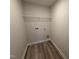 Small laundry room with wood-look flooring and a white wire shelf above the washer and dryer hookups at 9 W Emily Gardens Dr, Selma, NC 27576
