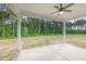 Covered back patio with ceiling fan, large concrete patio, and view of the expansive backyard with mature trees at 98 Laramie Ln, Selma, NC 27576