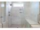 Modern bathroom shower with gray tiling, built-in shelf, shower bench, and glass doors at 102 E Star Foal Ln, Wendell, NC 27591