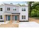 Inviting two-story gray duplex with blue doors, a covered entryway, and newly installed landscaping at 1047 |1049 E Harnett St, Dunn, NC 28334