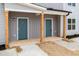 Close up of a modern gray duplex with wood columns and a covered entry highlighting two inviting blue doors at 1047 |1049 E Harnett St, Dunn, NC 28334
