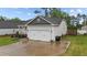 A two-car garage with a light gray exterior and black shingle roof offers ample parking space at 105 Jasper Creek Ct, Wilson's Mills, NC 27520
