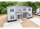 Aerial view of two-story new construction duplex with neutral siding, windows, front yard, and paved driveways at 1057 |1059 E Harnett St, Dunn, NC 28334