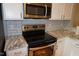 Stainless steel microwave and oven with white cabinets, complemented by marble countertops and backsplash at 108 W Savannah Ridge Rd, Holly Springs, NC 27540
